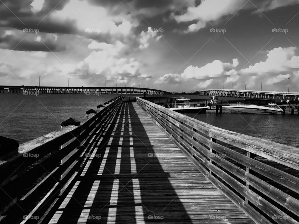 The long pier, bridges, boats and folks on a cloudy afternoon.