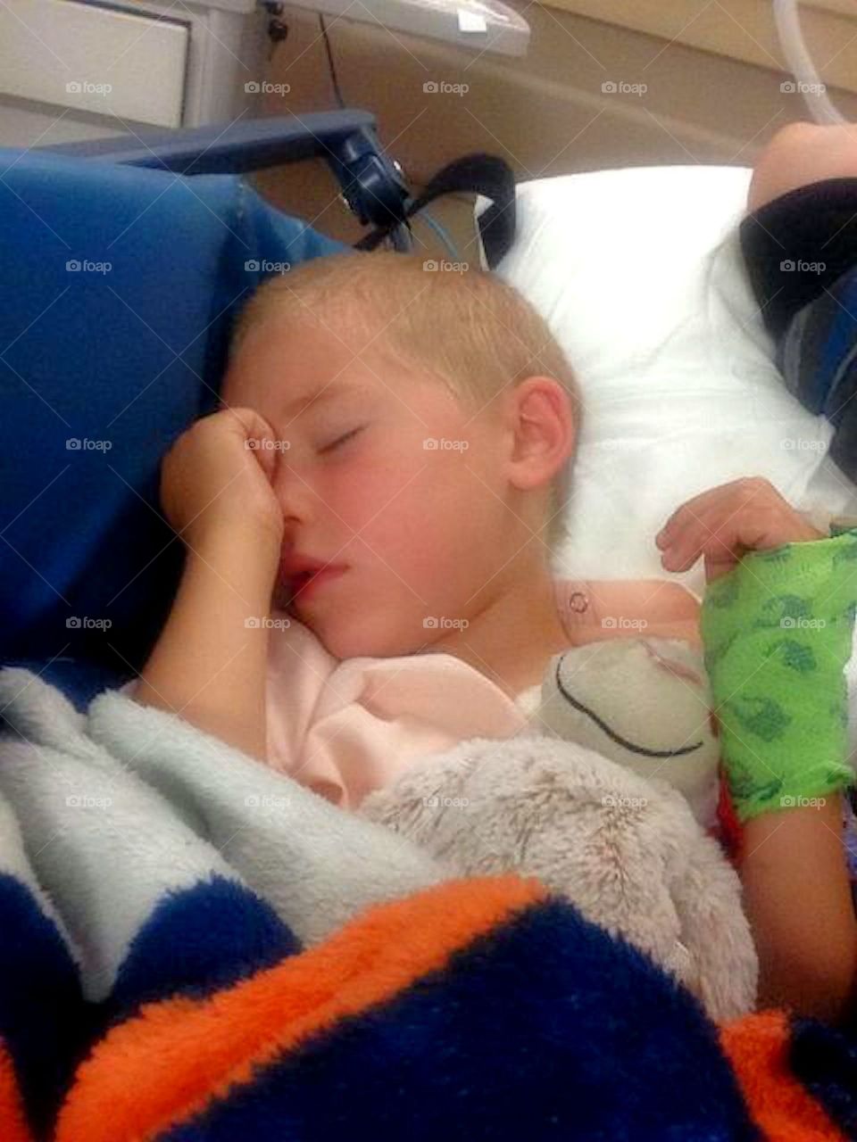 Recovery After Surgery. Young child waking up after getting his tonsils out at the hospital.