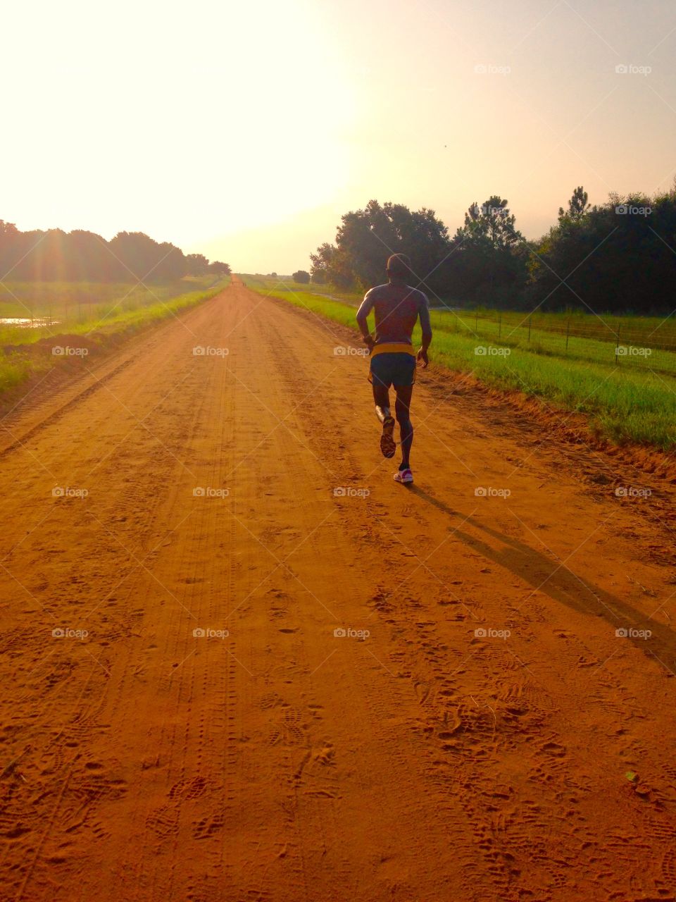 Lone runner on clay road. Lone runner on a clay road early in the morning.  
