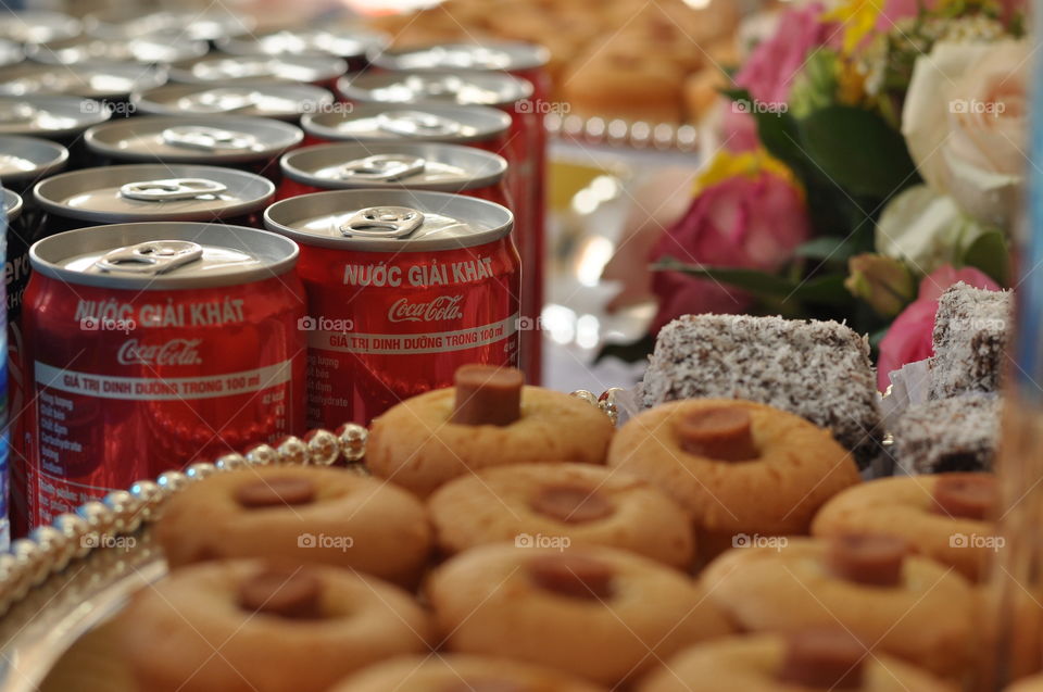 Coca-Cola cans, cake and flowers on table