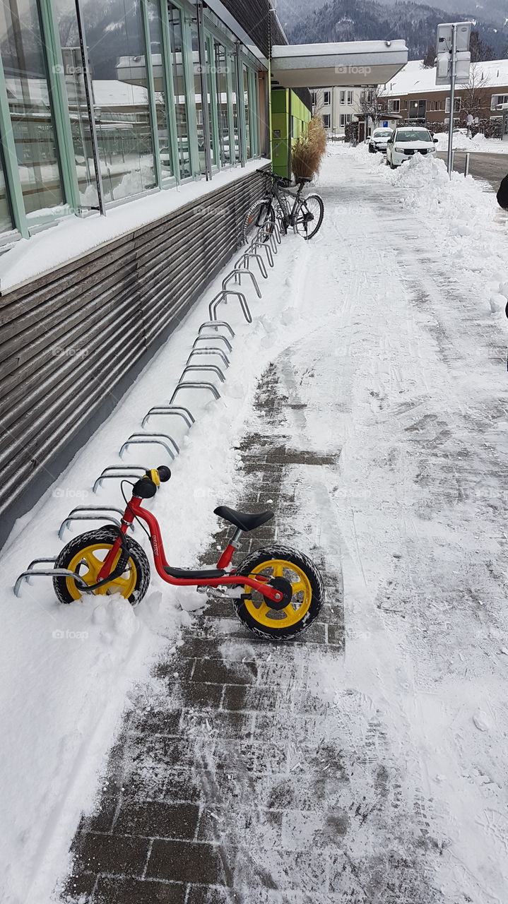 All in a days work. A small childrens bicycle parked outside a nursery school on a cold winters day.