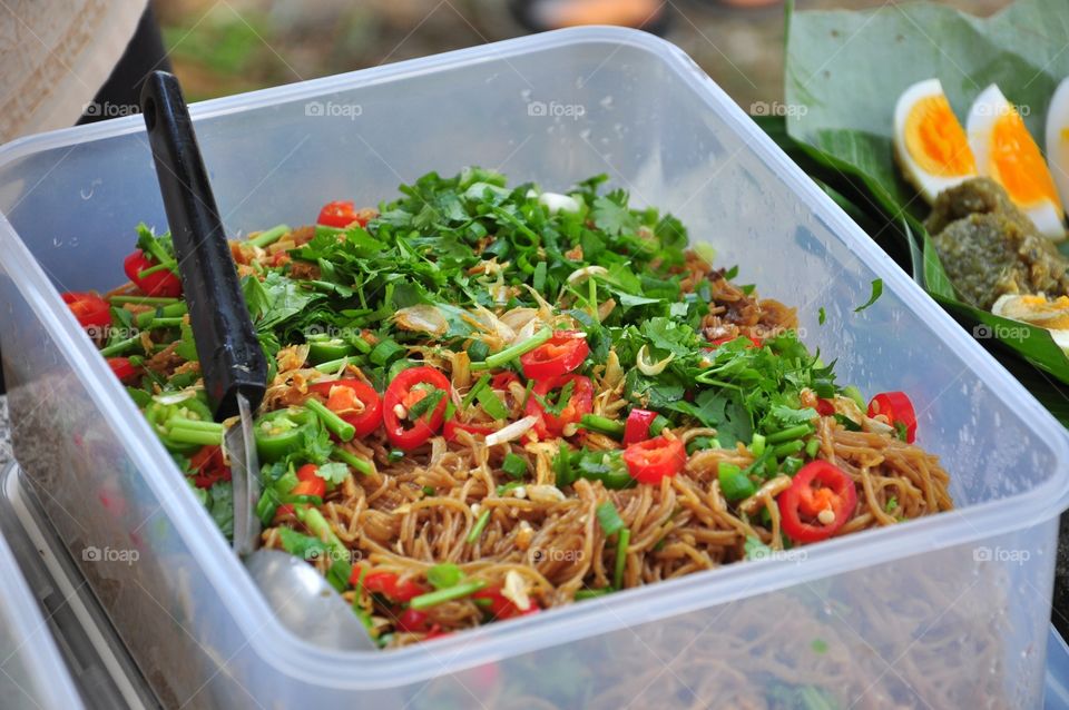 Fried chinese noodles with a ladle and corianders