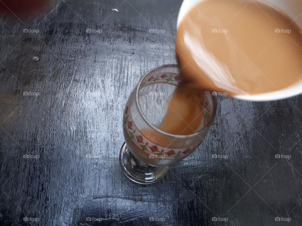Artistic design of how to pour mocha coffee between 2 glasses on a black wooden table