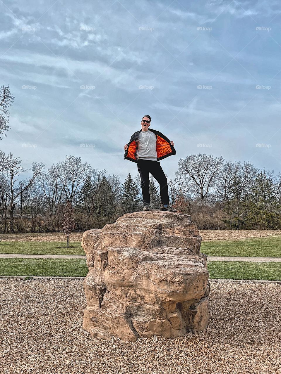 Man standing on top of large rock, rock climbing n the park, on top of the world, having fun at the park, being silly on top of a large rock, man on top of large rock in Ohio, Midwestern springtime fun, having fun in nature 