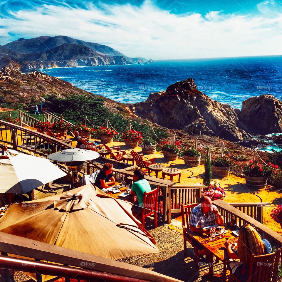 Rocky Point Restaurant off of Highway1. Patrons dining on the patio with spectacular view of California's rugged coastline and Bixby Bridge in the distance. 