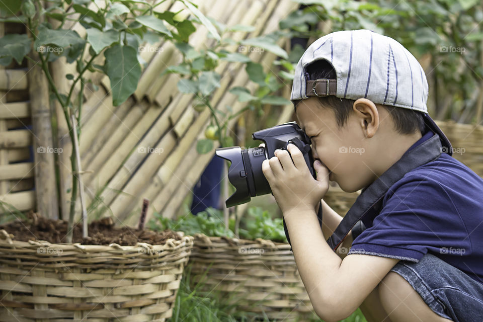 Hand boy holding the camera Taking pictures in park.