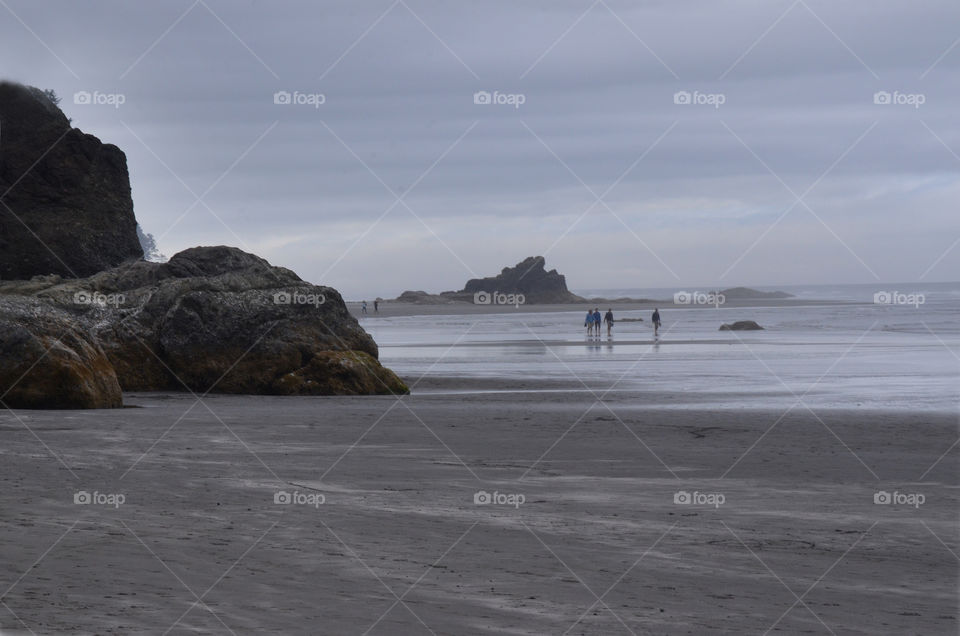 A group of friends walk along the shore of Ruby Beach in Washington state.