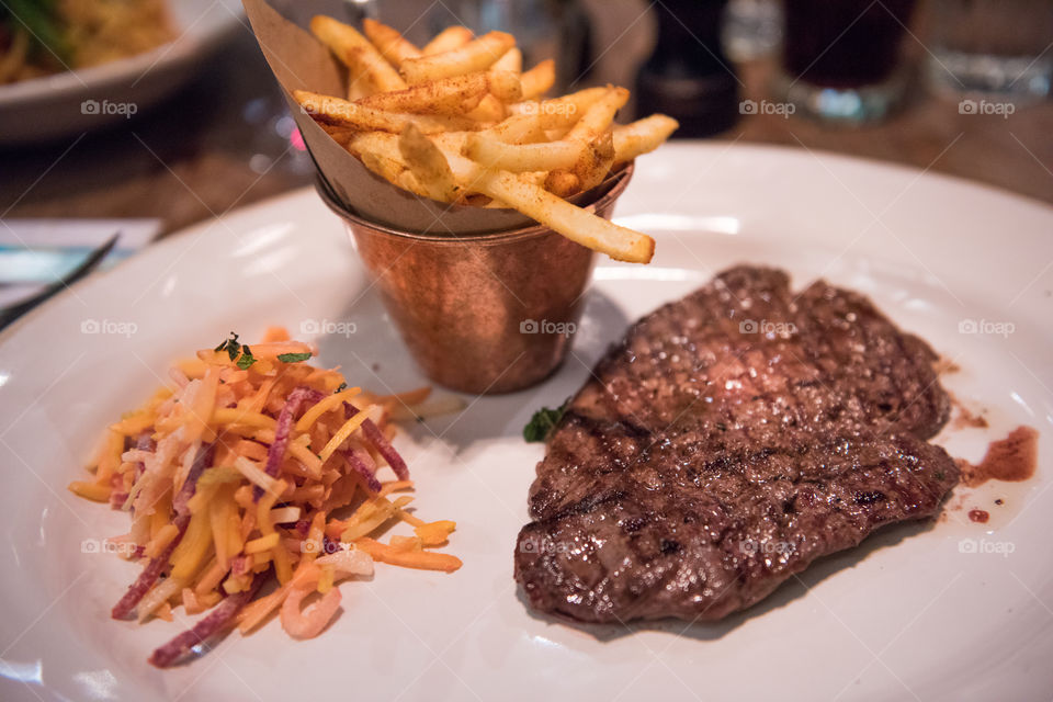 Main course at Famous Jamie's Italian restaurant in London. The restaurant has it's name after famous TV chef Jamie Oliver. Steak with fries and coleslaw.