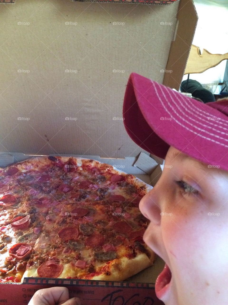 Close-up of a boy making face looking at pepperoni pizza