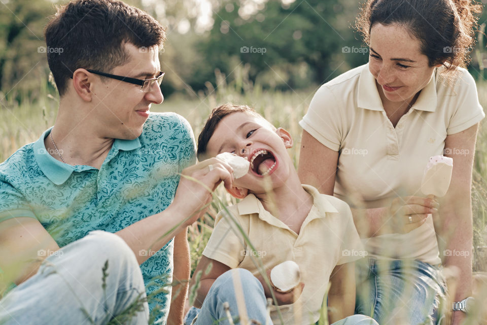 Happy laughing family eating ice cream on a picnic