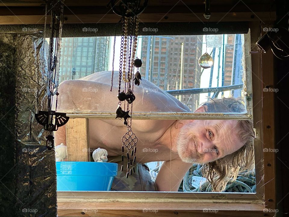 My fellow sailor “Timothy Trespas” looks into the window of our boat, the “28 ft 1969 Luhrs” at “Newtown Creek” in LIC, Queens after doing some repairs. Telling from his smile the job was a success. 2023. Hypnotic Productions