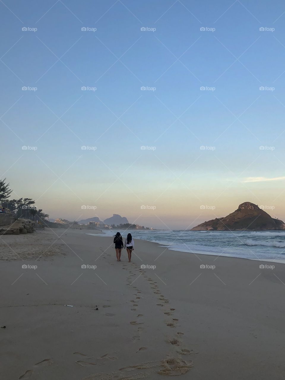 Two girls walking on the beach on a beautiful summer evening 