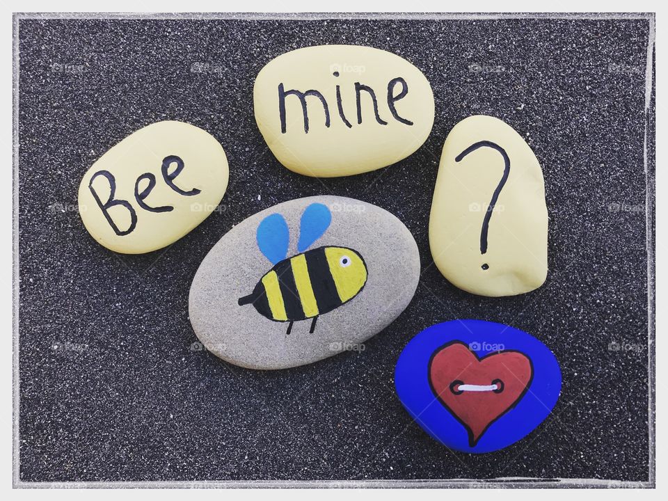 Bee mine ? Love message with stones design over black volcanic sand 