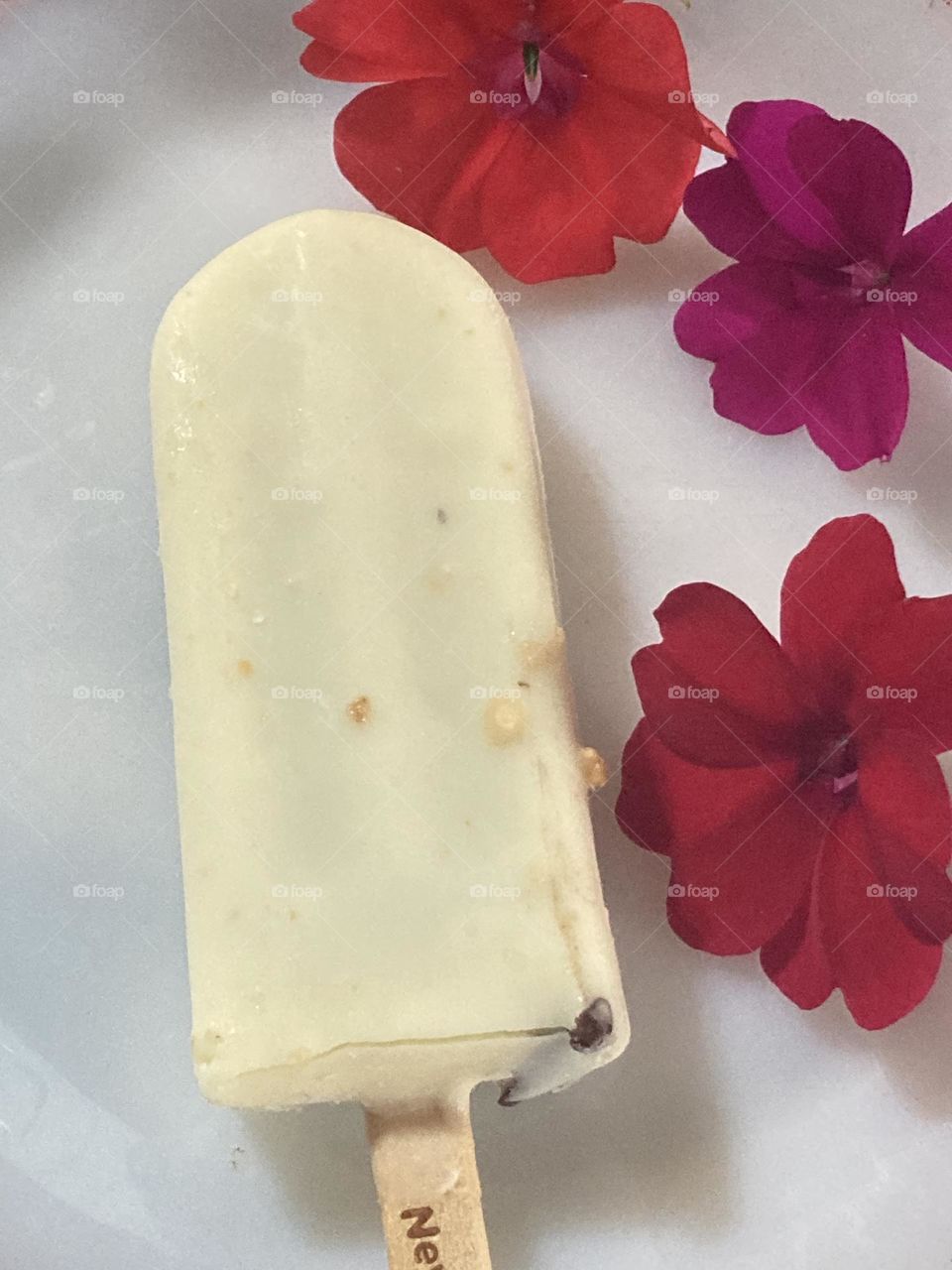 Sorvete cor creme é uma pontinha mostrando o chocolate. Sorvete com flores coloridas.