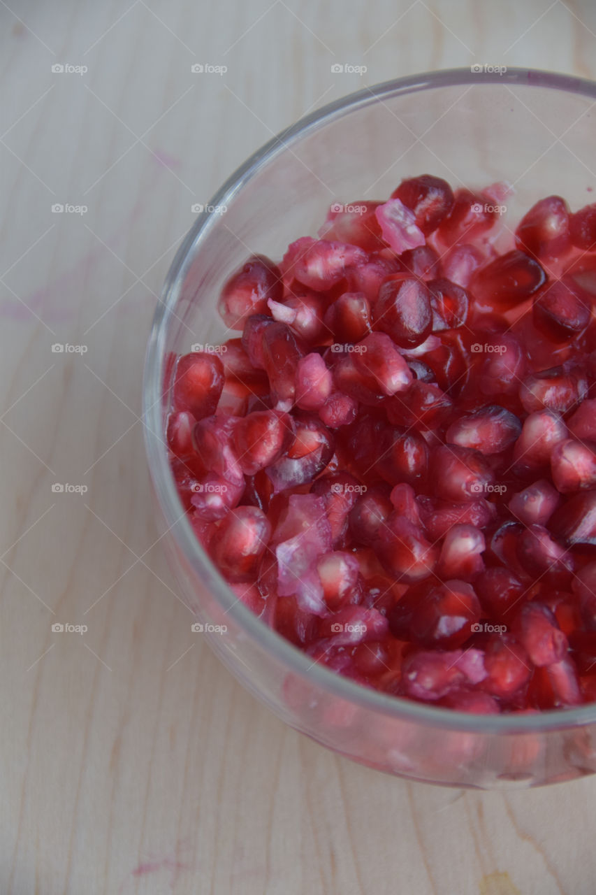 Exotic fruit, pomegranate seeds in a glass bowl on the butcher block