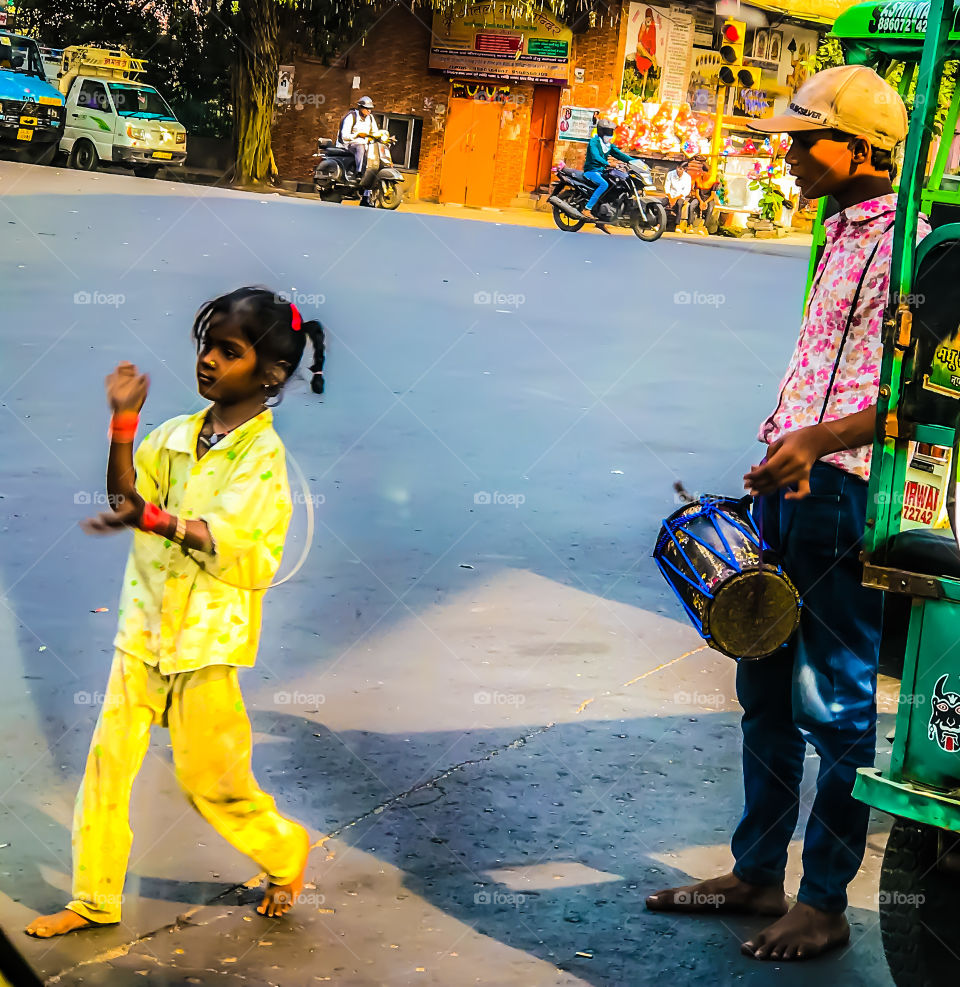 Little Girl with her brother entertaining people to earn money