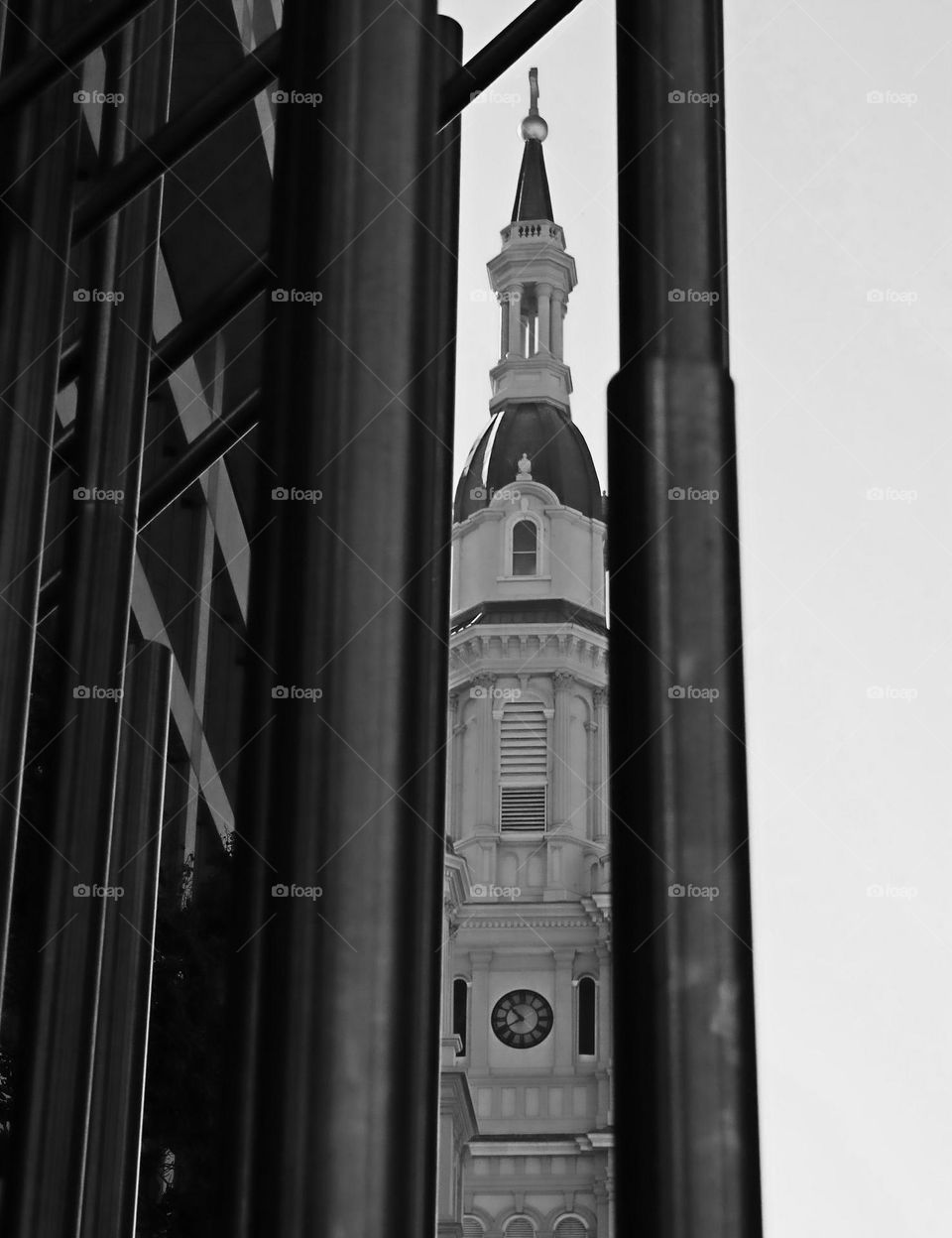 black and white view of a historical clock tower through metal artwork