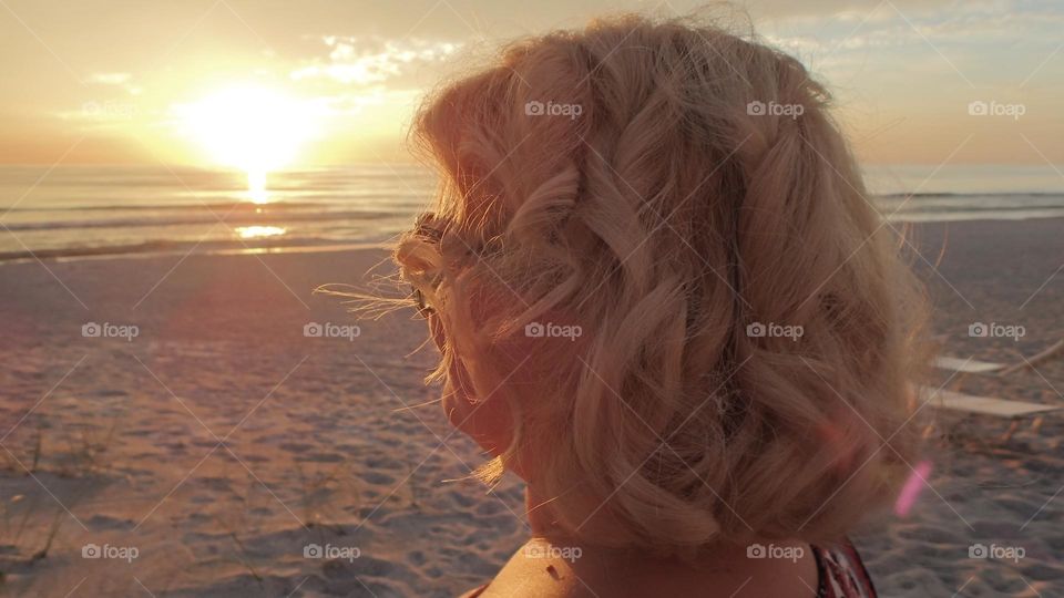Golden blonde curly luscious hair at golden sunset at the beach