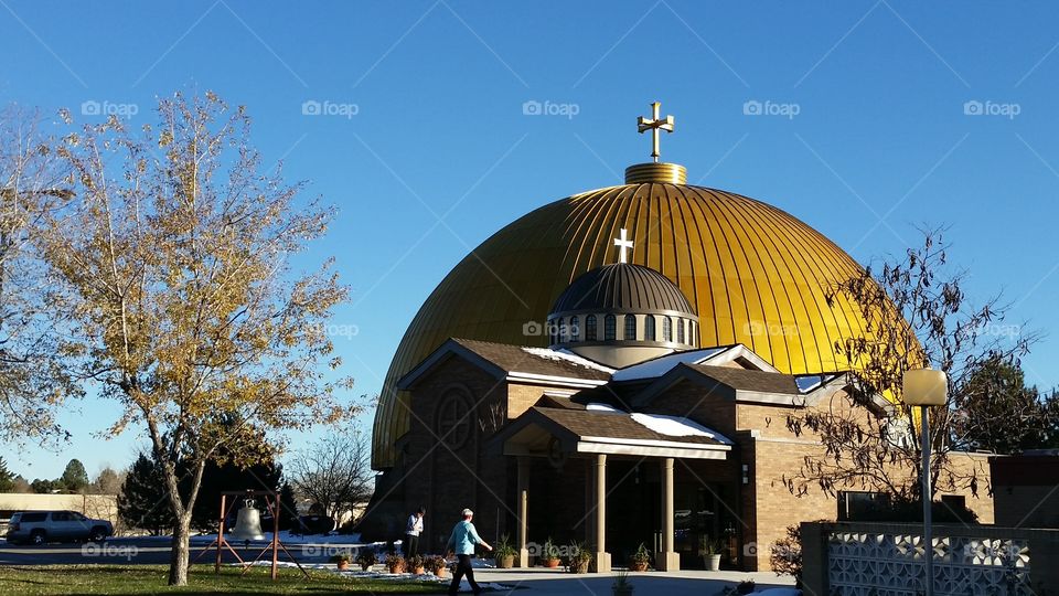 Golden church dome with cross with blue clear sky