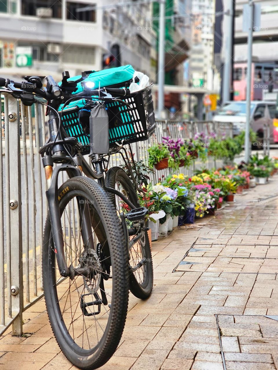 Bicycle parked on the street by the rail with colorful flowers