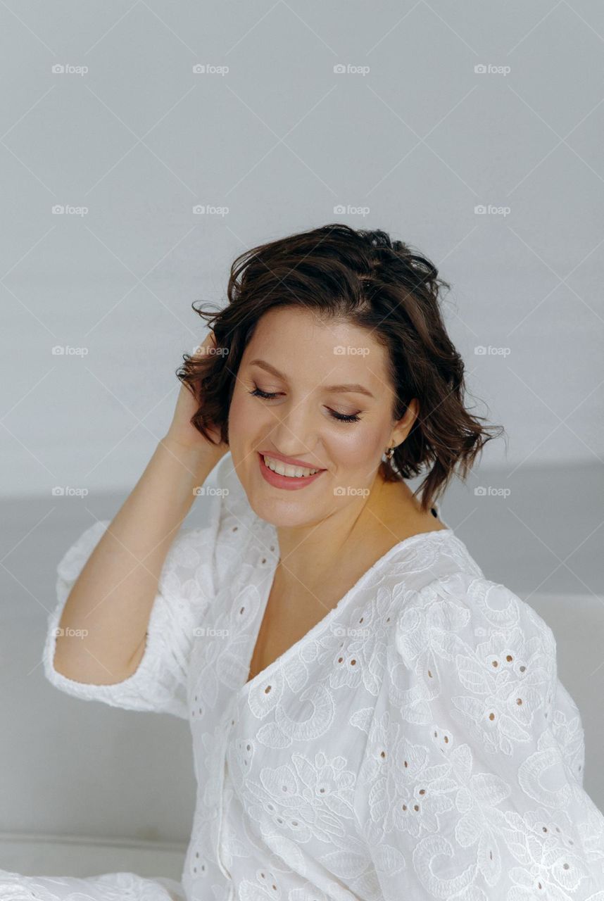 Happy brunette girl in white dress smile and straighten hair
