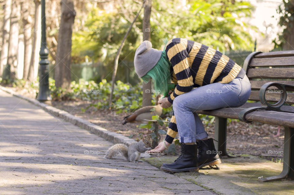 Alternative girl in the park feeding a squirrel