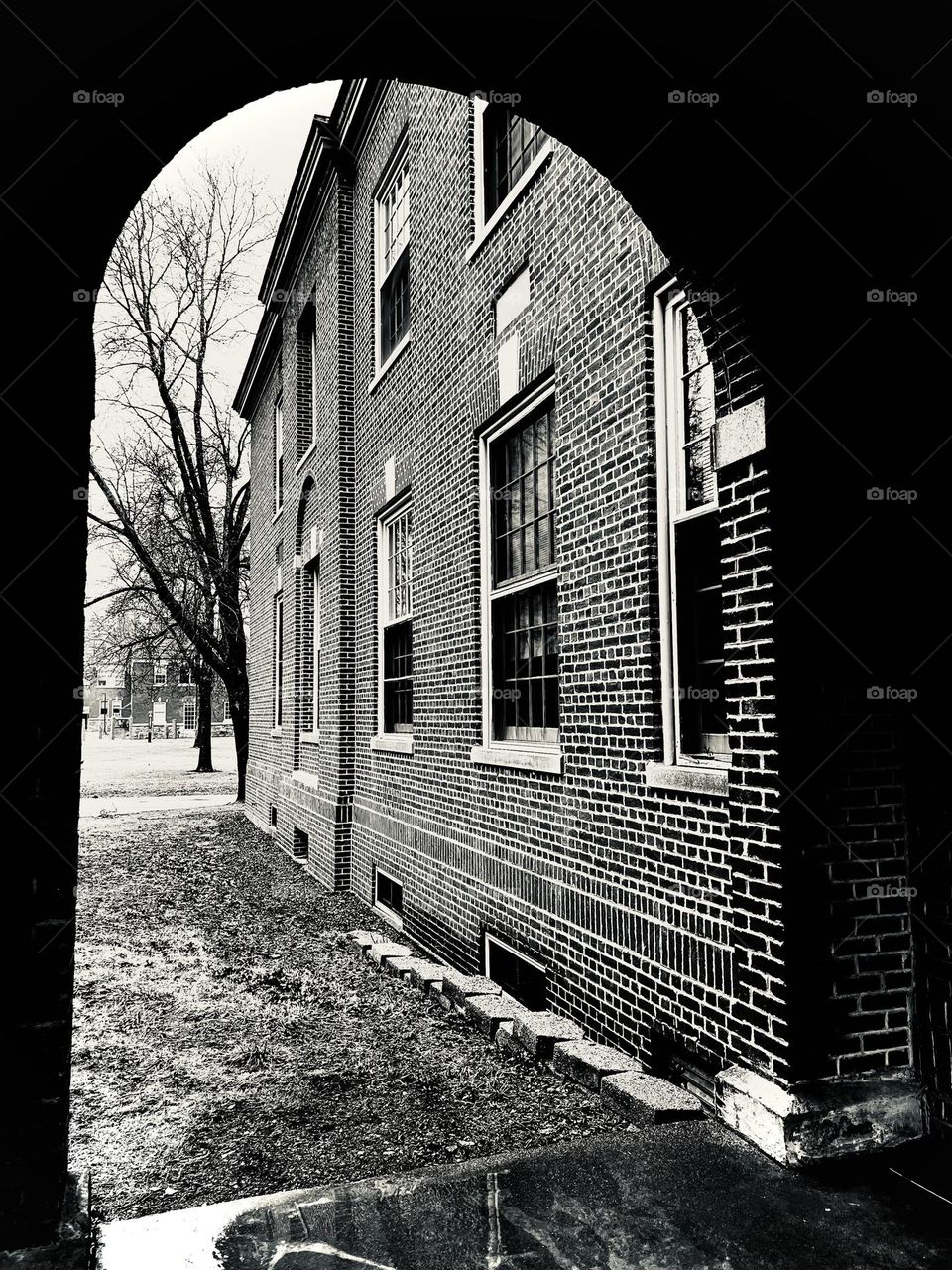A brick archway connects to a brick building on college campus.