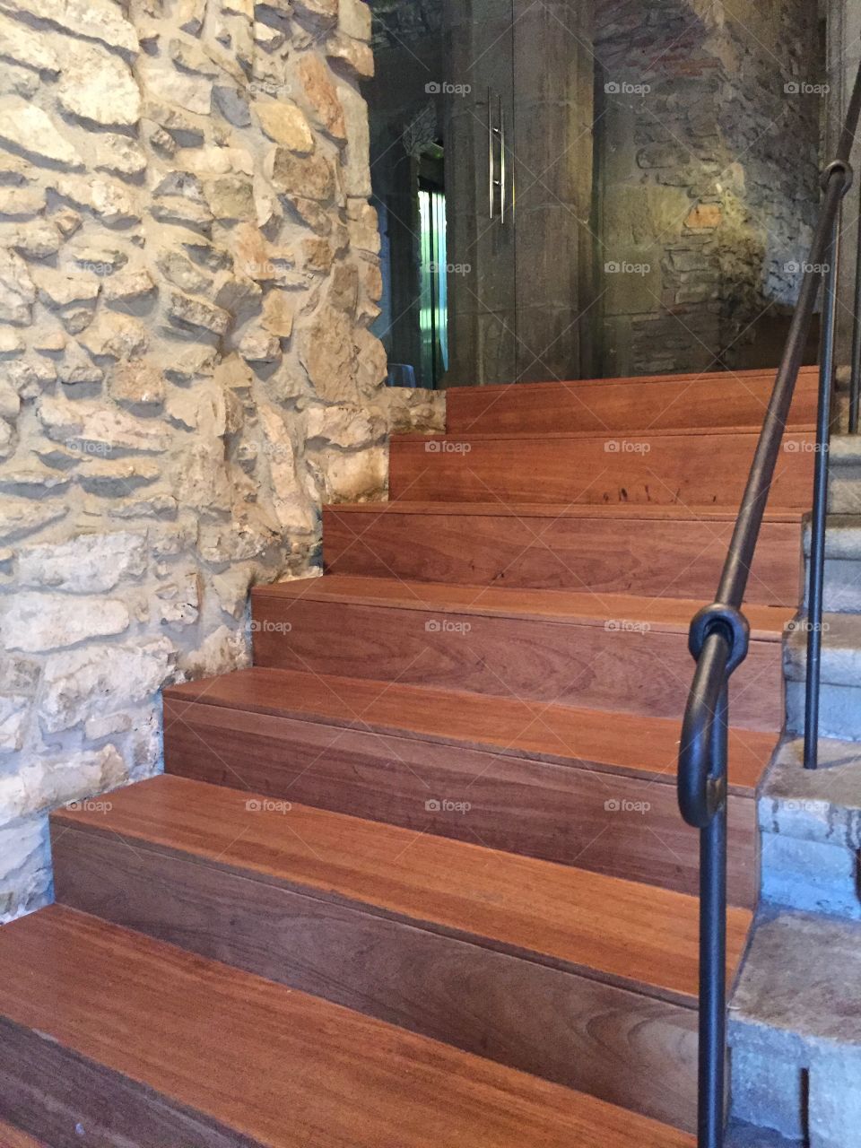 Modern wooden steps and iron rail in historic stone structure; luxury stairs 