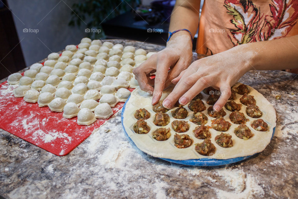 Woman Making Dumplings In Kitchen At Home