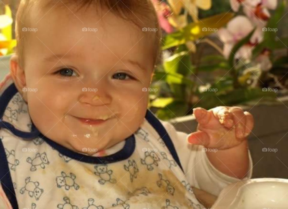 happy little baby with chubby cheeks covered in dinner.