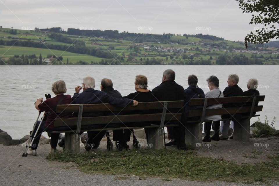 Elderly People. Elderly people sitting on a bench facing the lake Sempachersee in Luzern,central Switzerland.