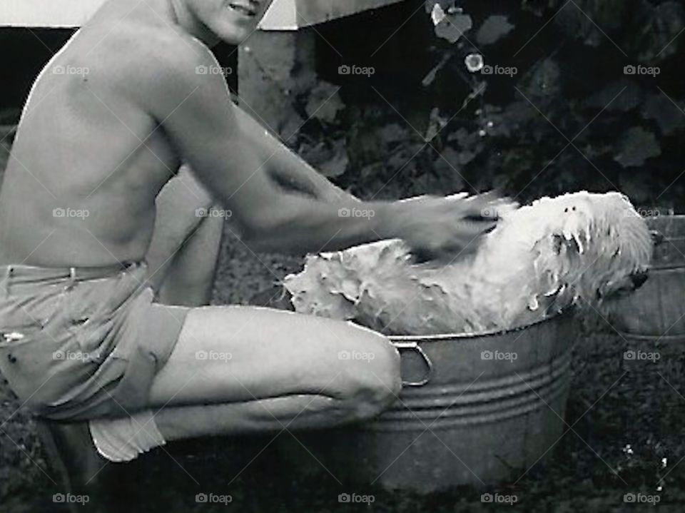 Dad washing dog in old tub outdoors