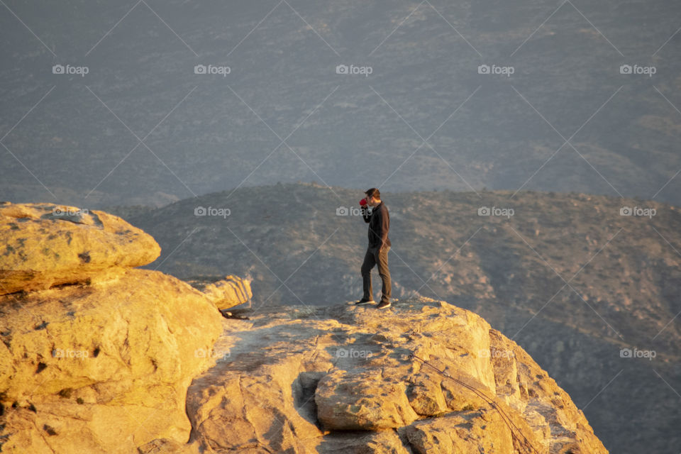 A man sipping a coffee during sunset on the mountain