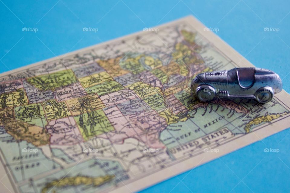 Miniature silver racer heading west on a miniature vintage map of the United States of America against a sky blue background
