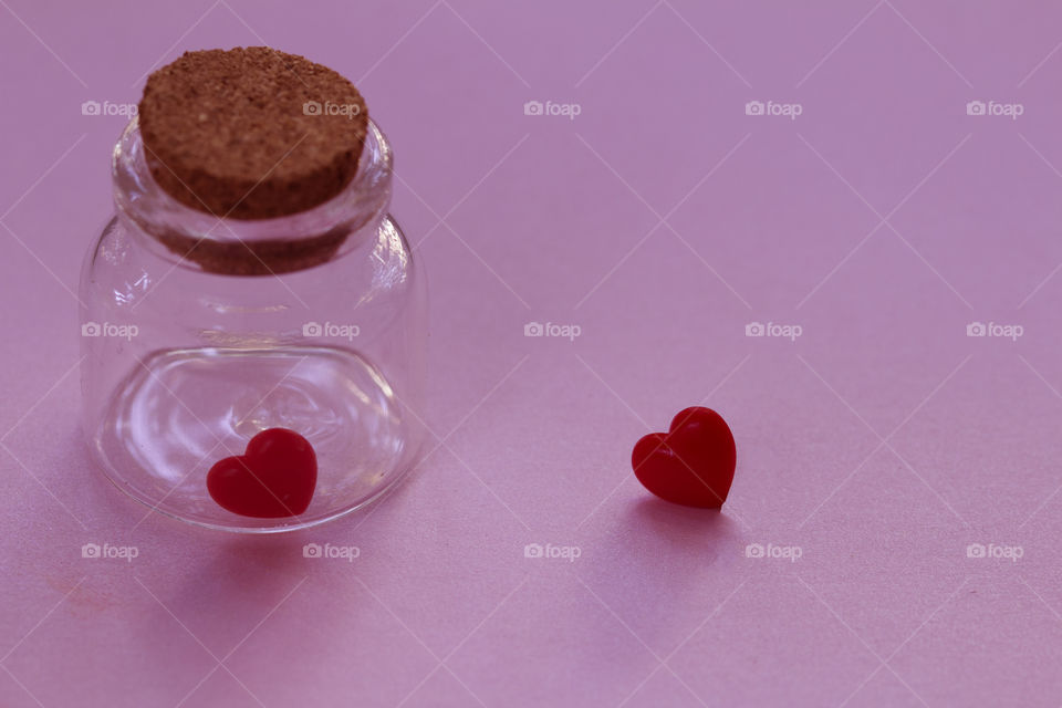 Red heart in the bottle glass and one heart out of the bottle . 
Forbidden and failed love concept