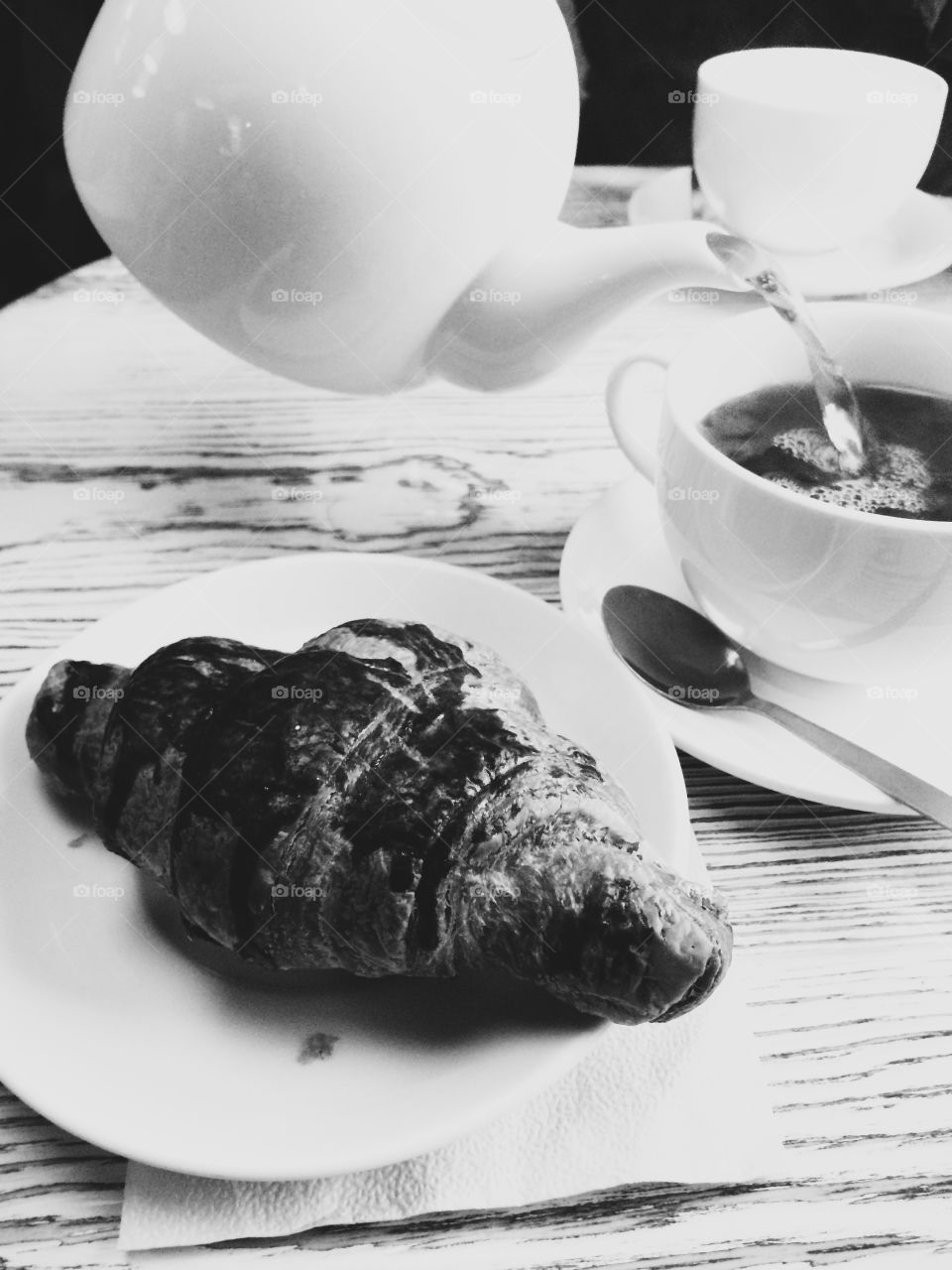 Still life composition of a croissant and cup of tea.