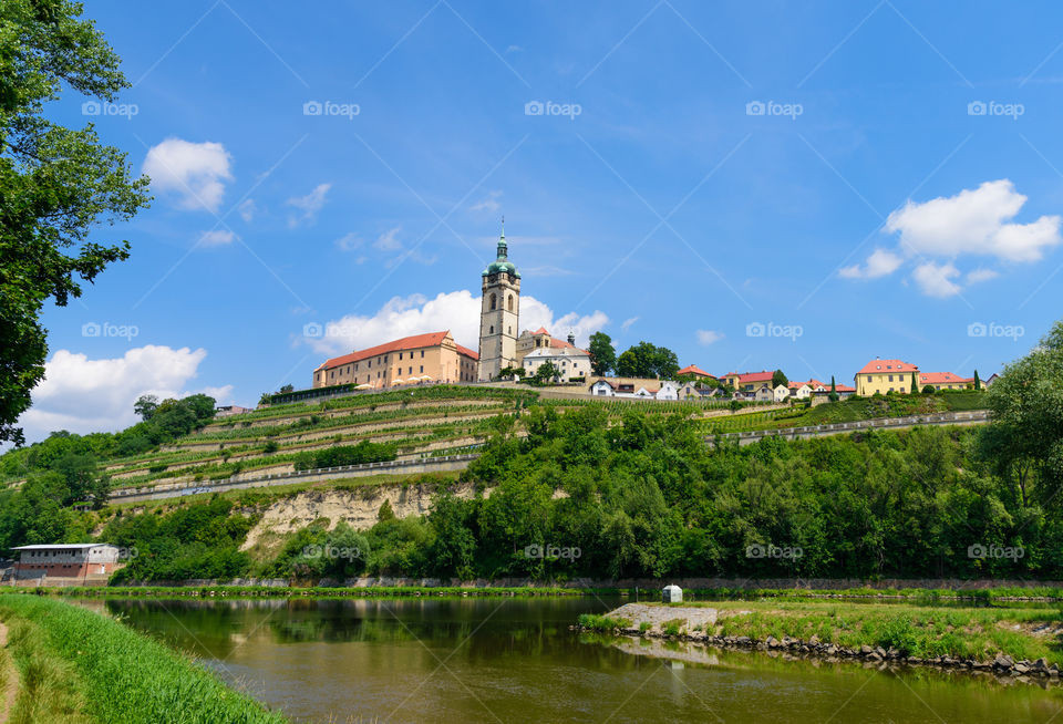 The historic Mělník castle and church tower of St. Peter and Paul at the confluence of the Vltava (Moldau) and Labe (Elbe) rivers on sunny early July afternoon in 2017 in Mělník, Czech Republic.