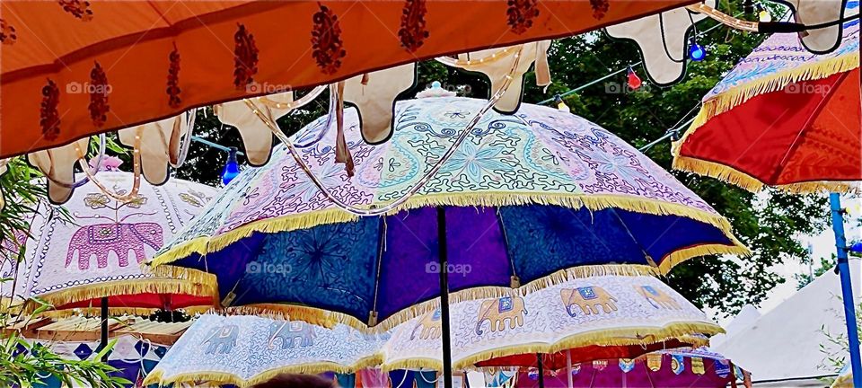 Beautiful patterned umbrellas cover the stands at the “Tollwood” summer festival in “Munich”, Bavaria that presents music as well as a large market for folklore fare, arts and crafts and merchandise from around the World. 2024. Hypnotic Productions