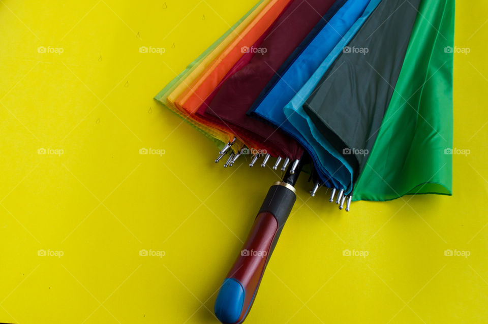 Colorful umbrella with yellow colored background.