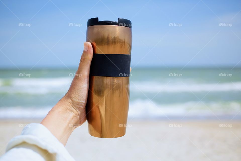 Golden portable cup at sea background 