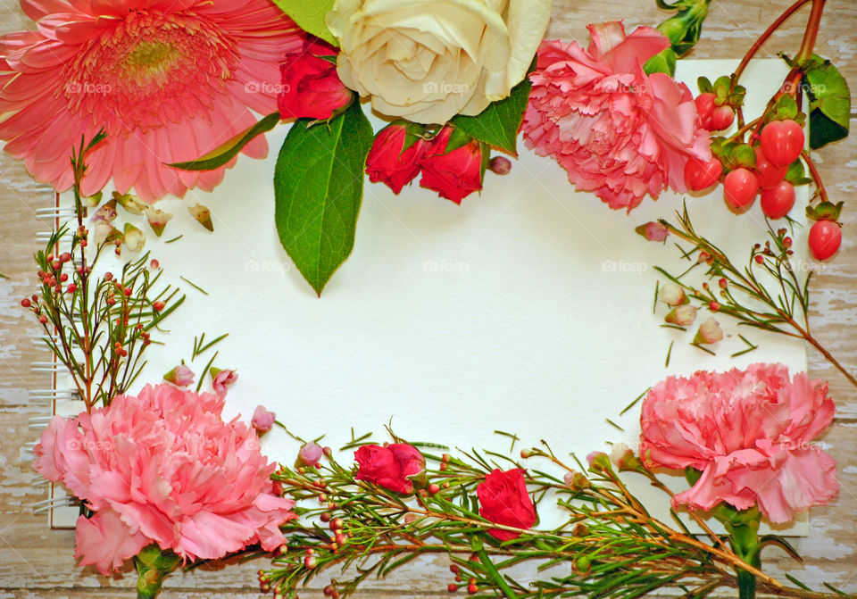 Spring, flowers, floral border, flower border, flat lay, white paper, wooden background, pink flowers and leaves, carnations, landscape orientation