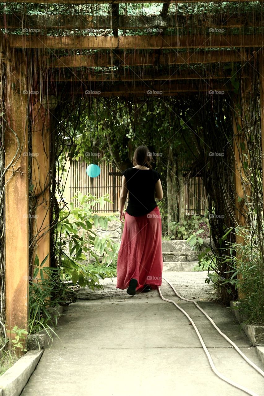 woman walking through a garden covered canopy