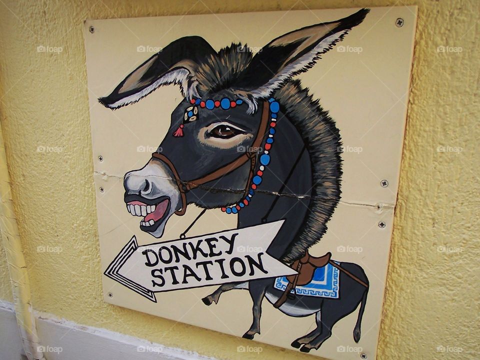 Sign in Oia, village on the island of Santorini  in Greece; directions to the donkey station