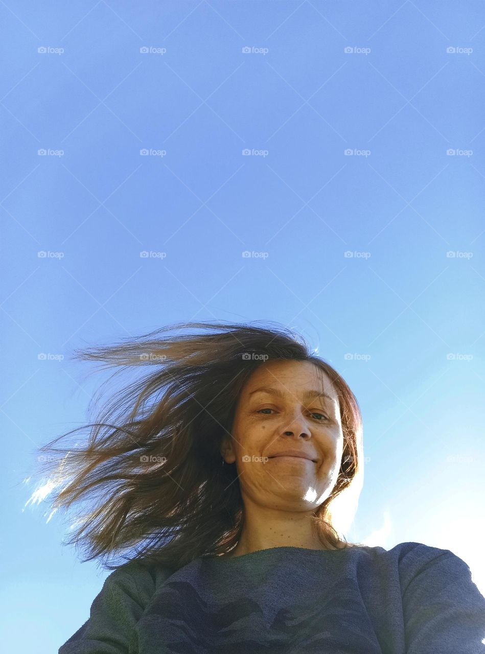 selfie woman view from the ground, blue sky background