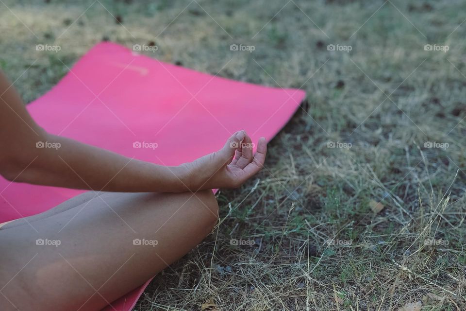 a girl in a black tracksuit, on a pink rug in the forest, does yoga, the girl meditates