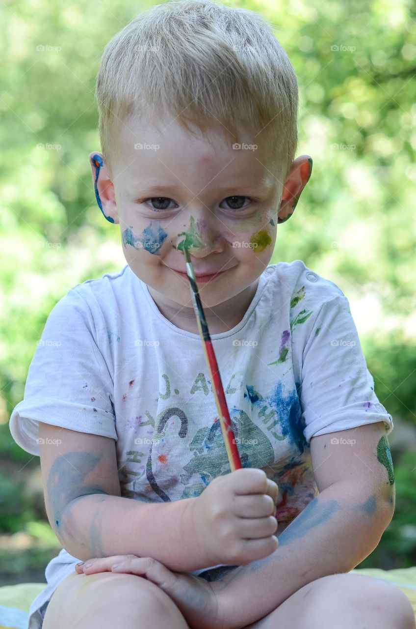 Boy smeared with paint while painting.