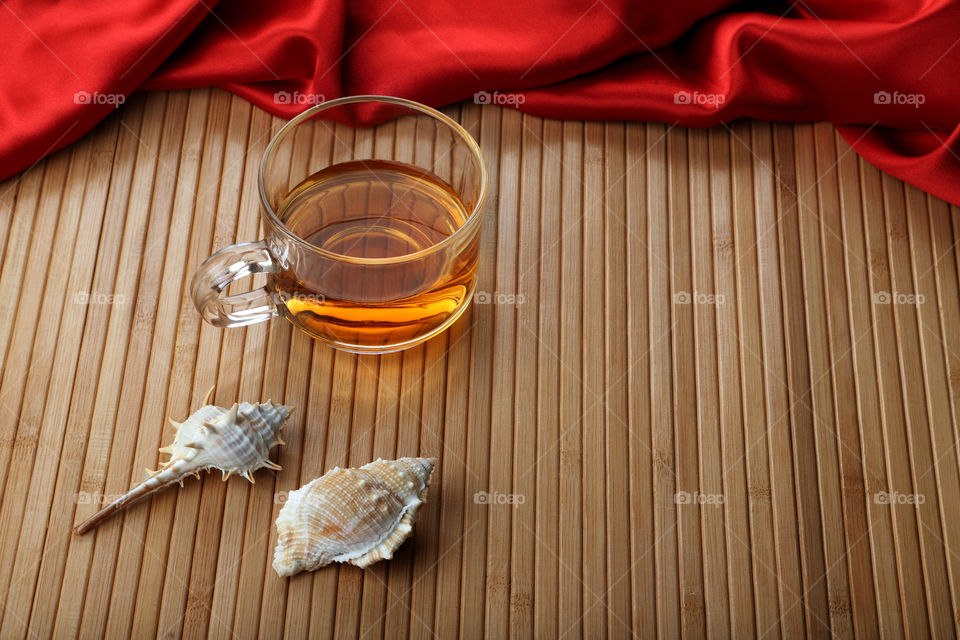 A cup of tea on wooden background with seashells