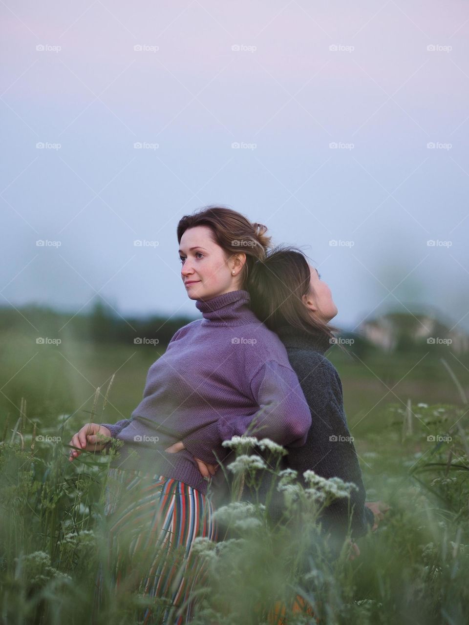 Two young beautiful woman’s standing in field on a summer day, portrait of woman 