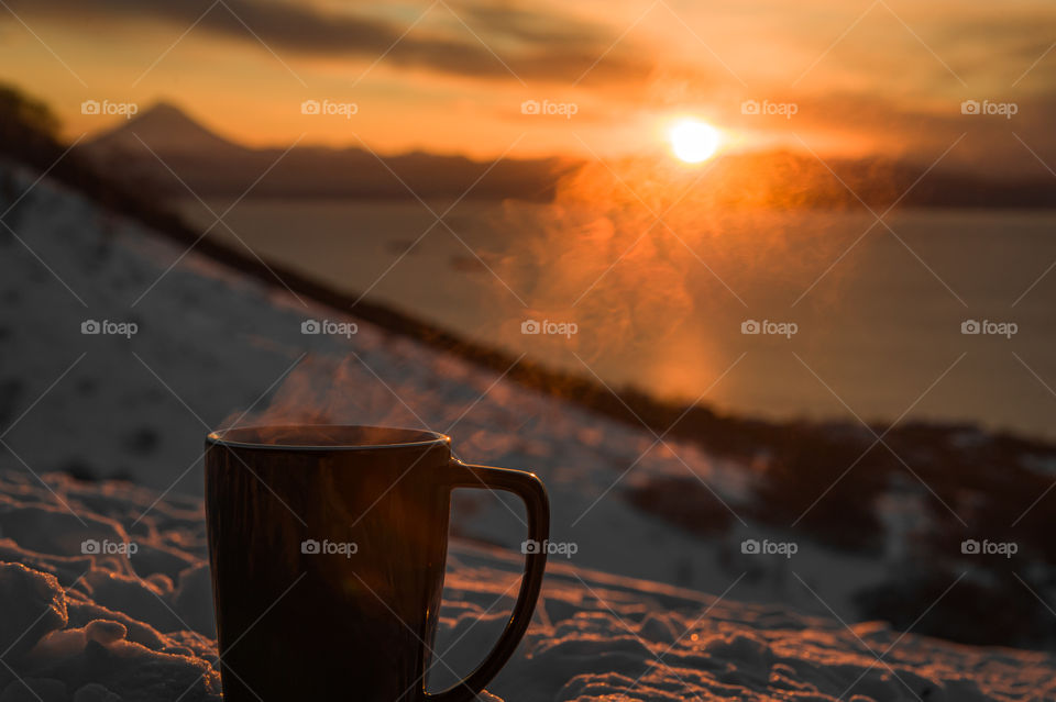 coffee mug stands in the cold and soars against the sunset