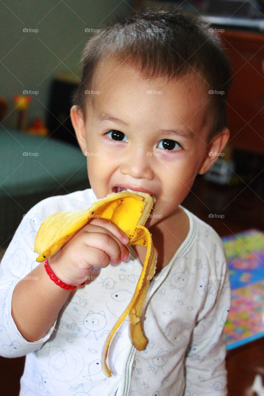 young boy eating banana 